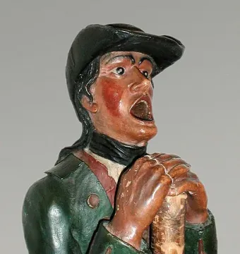 Aschaffenburger Maulaff painted wooden bust with a dark cap, green jacket, and open mouth