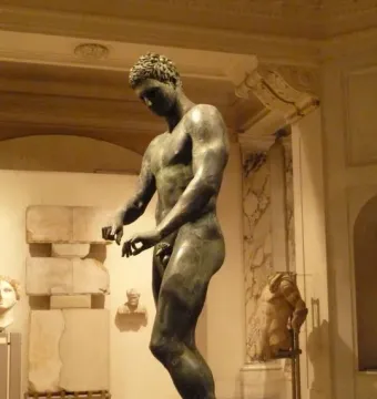 Bronze statue of the Athlete from Ephesus standing indoors in a museum gallery.