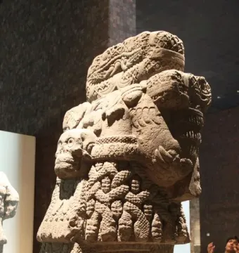 Coatlicue stone statue with serpent heads, skull necklace, and carved textured body