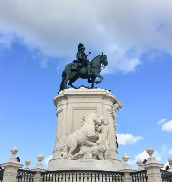 Equestrian statue of Joseph I on a tall ornate pedestal against a blue sky.