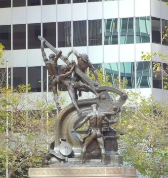 Mechanics Monument bronze sculpture of muscular men operating industrial machinery on a stepped stone pedestal.