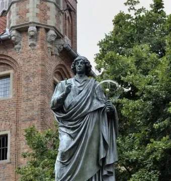 Nicolaus Copernicus Monument showing a bronze statue of a robed man pointing upward and holding a celestial globe.