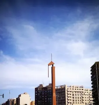 Pink Panther sculpture rising from a paved plaza with residential buildings behind it.