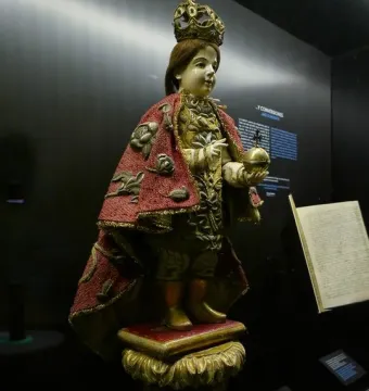 Santo Niño de Cebú statue with a golden crown, red embroidered cape, and golden orb with cross.