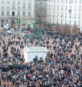 Louis XIV equestrian statue on a pedestal in a crowded public square.