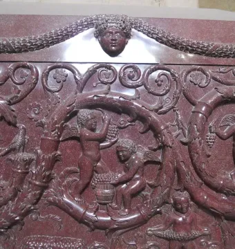 Sarcophagus of Constantina relief with winged putti harvesting grapes among swirling vine motifs and a central human head.