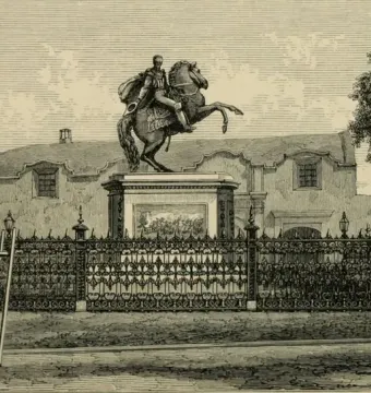 The Equestrian Statue of Simón Bolívar, showing a cloaked figure on a rearing horse atop a tall pedestal behind an ornate iron fence.