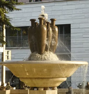 Fountain of the Frogs with a tiered stone basin and dark jugs on the top tier.