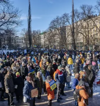 Johan Ludvig Runeberg Statue overlooking a large crowd gathered in a snowy Helsinki park.