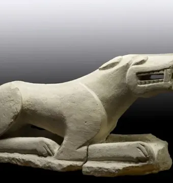 Leona de Baena stone sculpture shown in side profile, with an open mouth and extended paws.