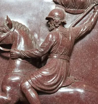 Close-up of a relief on the Sarcophagus of Helena showing a helmeted warrior on horseback raising a spear.