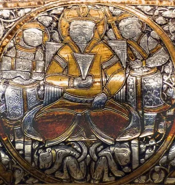 Circular medallion from the Baptistery of Saint Louis showing a central ruler holding a cup, flanked by two attendants, with silver foliage and small animals around the base.