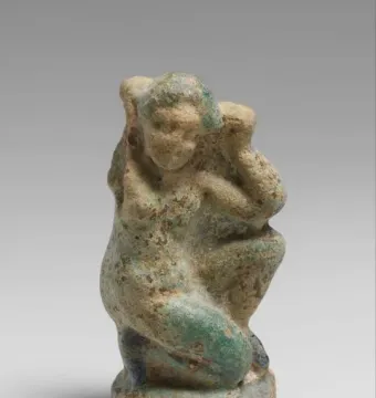 Crouching Venus statuette of a crouching female figure with one arm raised and the other across her body.