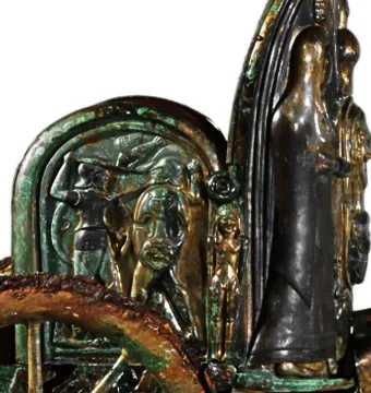 Detail of the Monteleone Chariot showing a bronze relief panel with figures in battle and ornate decorative elements.