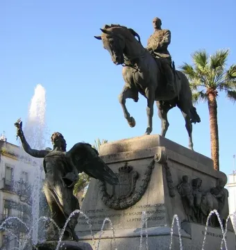Monument to Primo de Rivera with a bronze horse and rider atop a tall stone pedestal and a winged figure below, with a fountain spraying in front.