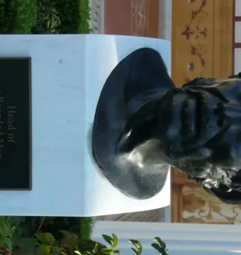 Pseudo-Seneca bronze bust of a bearded man on a white marble pedestal with an informational plaque.
