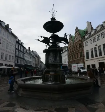 Stork Fountain with three bird sculptures above a bronze bowl in a Copenhagen square.