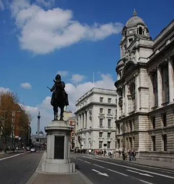 Duke of Cambridge equestrian statue on a stone plinth in a busy London street.
