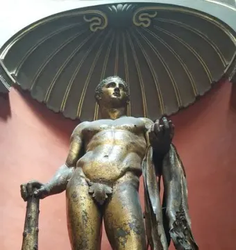Hercules standing in a shell-shaped niche, holding a club and a lion skin, with a fig leaf covering his groin.