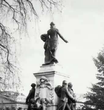 Marquis de Lafayette statue seen from behind, standing on a tall pedestal with figures around the base.