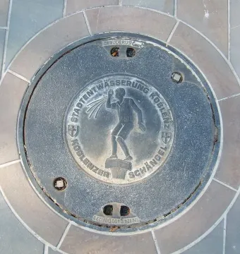 Koblenz Schängel embossed on a circular metal manhole cover with German text and coats of arms.