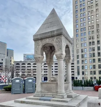 Bagley Memorial Fountain with a pointed roof and carved stone arches in an urban plaza.