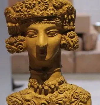 Lady of Ibiza clay figurine with elaborate headdress, necklaces, and decorated dress