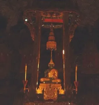 The Emerald Buddha seated on an ornate golden pedestal beneath a decorative canopy.