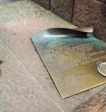 Bronze plaque on the Heidelberg Bridge Monkey sculpture with engraved German text and two small bronze mice on a stone block.