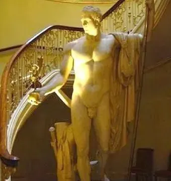 Napoleon as Mars the Peacemaker statue beside a grand staircase with ornate golden railings.