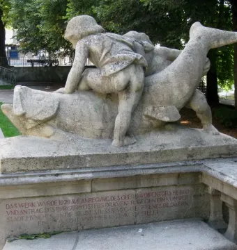 Rhine Water Fountain sculpture with two figures seated on a fish-like creature above a shallow pool.