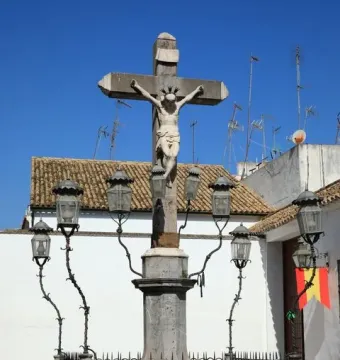 Christ of the Lanterns crucifix in Córdoba, illuminated by ornate black lanterns and surrounded by a decorative iron fence.