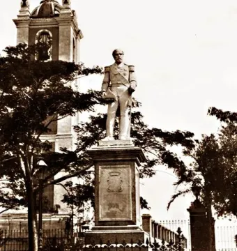 The Count of Porto Alegre monument, a statue of a uniformed figure on a raised plinth behind an iron fence, with a domed building in the background.