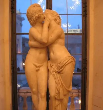 Marble sculpture of Cupid and Psyche embracing and kissing on a pedestal.