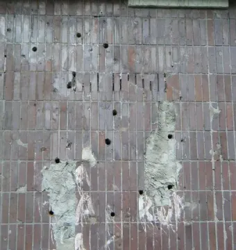 Worn Plon relief wall with reddish-brown vertical tiles, missing patches, and white residue