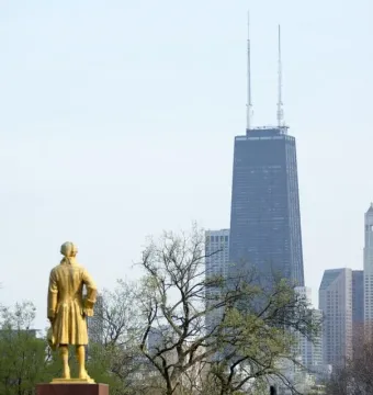 Alexander Hamilton statue seen from behind, with Chicago skyscrapers in the background.