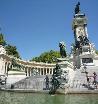 Alfonso XII Monument with a central column and equestrian statue, surrounded by a colonnade beside the lake