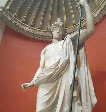 Antinous Braschi, a white marble statue of a youthful male figure with a bare torso, draped cloth, curly hair, and a raised staff.