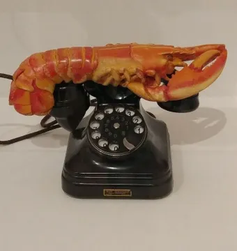 Lobster Telephone sculpture combining a black rotary phone with a bright red-orange lobster on the receiver cradle.