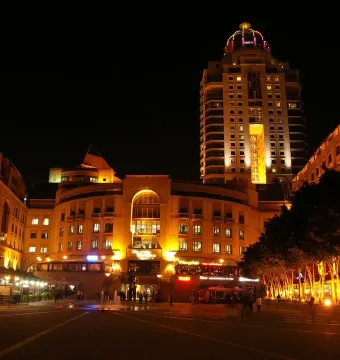 Nelson Mandela statue silhouetted in a brightly lit city square at night.