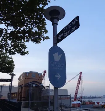 Directional signs for Ballpark Station and the Staten Island September 11 Memorial on a street pole near the waterfront.
