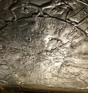 The Dendera Zodiac relief, showing a circular ancient Egyptian carving with figures and symbols around a central disk.