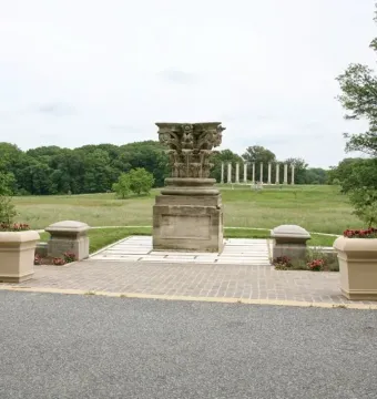 Capitol Columns standing across a grassy field with an ornate stone capital in the foreground