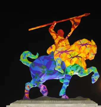 El Cid on a rearing horse wrapped in multicolored crocheted yarn.