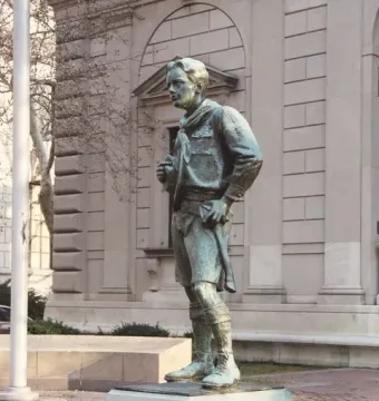 The Ideal Scout statue stands on a stone base in a paved plaza.