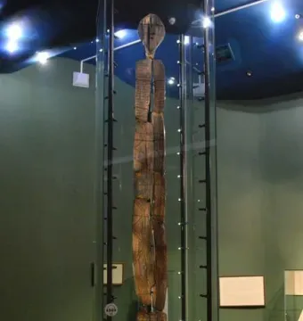 The Shigir Idol, a tall carved wooden figure displayed in a museum glass case.