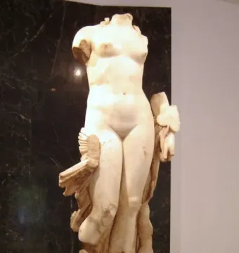 Venus Unica, a headless white stone female nude statue on a rectangular base.