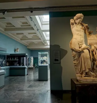 Apollo of Cyrene marble statue with draped lower body, a lyre, and a serpent at the base