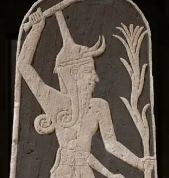 Stele of Baal with a horned deity raising a thunderbolt and holding a spear, with a smaller figure beside him.