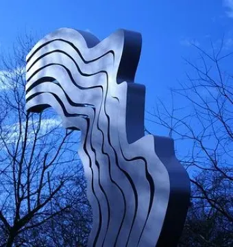 De Schreeuw sculpture against a deep blue sky with leafless tree branches
